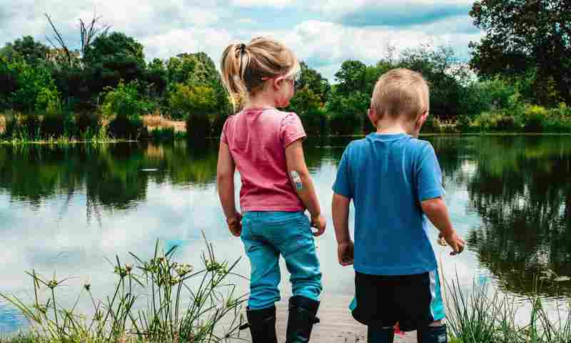Pige og dreng kigger ud over en sø
