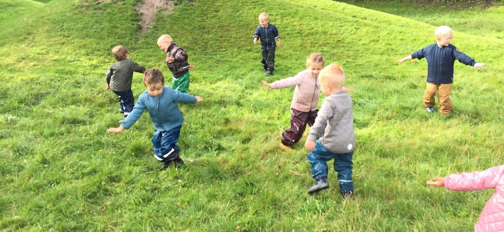 Børn løber rundt i tumler på en græsplæne