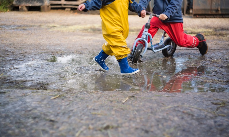 To børn leger i vandpytter To børn leger i vandpytter